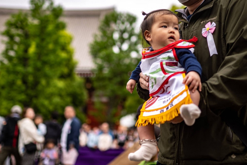 یک پدر و مادر فرزند خود را قبل از مسابقه "Baby-cry Sumo" در معبد Sensoji در توکیو در روز شنبه در آغوش می گیرند | خبرگزاری فرانسه-جیجی